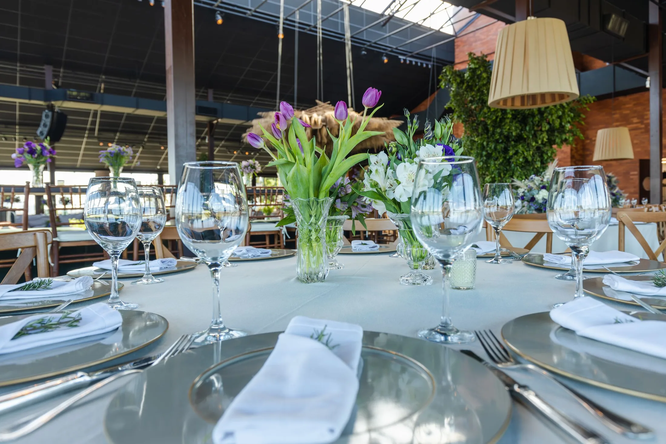Mesa posta com taças, louças claras e arranjo de flores; fotografia licenciada ilustrativa